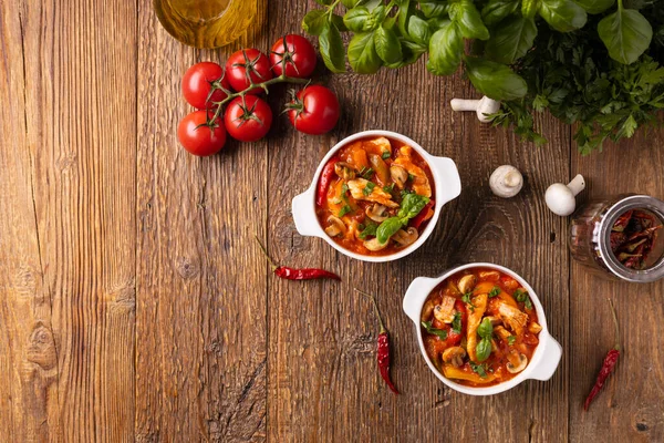Chicken stew with peppers, mushrooms and tomatoes. Wooden background. 