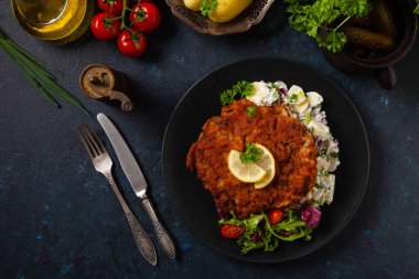 Klasik, geleneksel Viyana sığır filetosu şnitzel. Patates salatasında servis edildi. Üremiş. Koyu arkaplan.