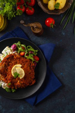 Klasik, geleneksel Viyana sığır filetosu şnitzel. Patates salatasında servis edildi. Üremiş. Koyu arkaplan.