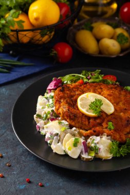 Klasik, geleneksel Viyana sığır filetosu şnitzel. Patates salatasında servis edildi. Üremiş. Koyu arkaplan.