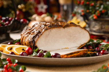 Fırında jambon. Noel süsü. Yabanmersini ve portakalla servis edilir. Pişirme sırasında iple bağlanmış. Tahta masa..