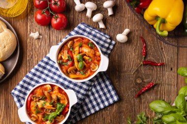Chicken stew with peppers, mushrooms and tomatoes. Wooden background. 