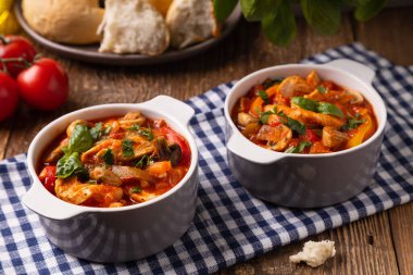 Chicken stew with peppers, mushrooms and tomatoes. Wooden background. 