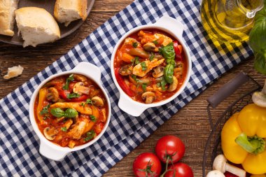 Chicken stew with peppers, mushrooms and tomatoes. Wooden background. 