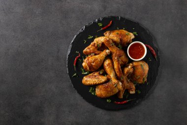 Fırında tavuk parçaları karışımı. Acı sos ya da patates kızartması ile servis edilir. Koyu arkaplan.