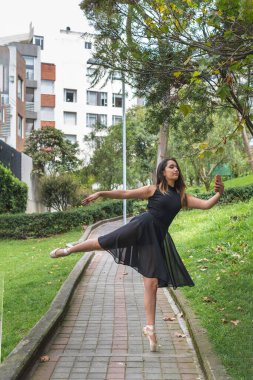 Maskeli balerin parkta selfie çekiyor.