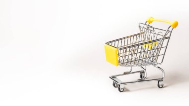 Fotokopi alanı olan gri bir arkaplanda minyatür alışveriş arabası izole edilmiş.