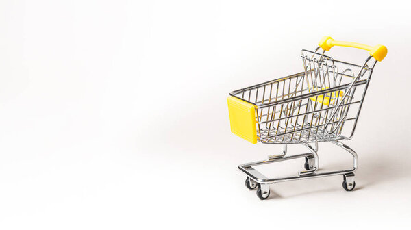 Miniature shopping cart isolated on a gray background with copy space
