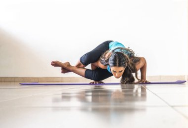 Latin esmer kadın yoga yapıyor. Sekiz Açı Poz veya Astavakrasana