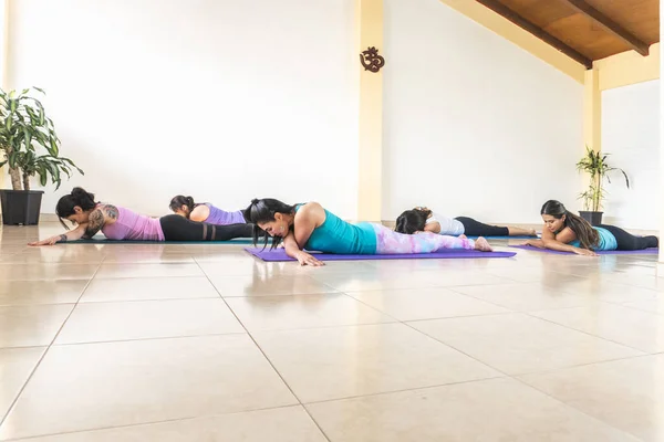women practicing yoga and relaxation lying face down in studio
