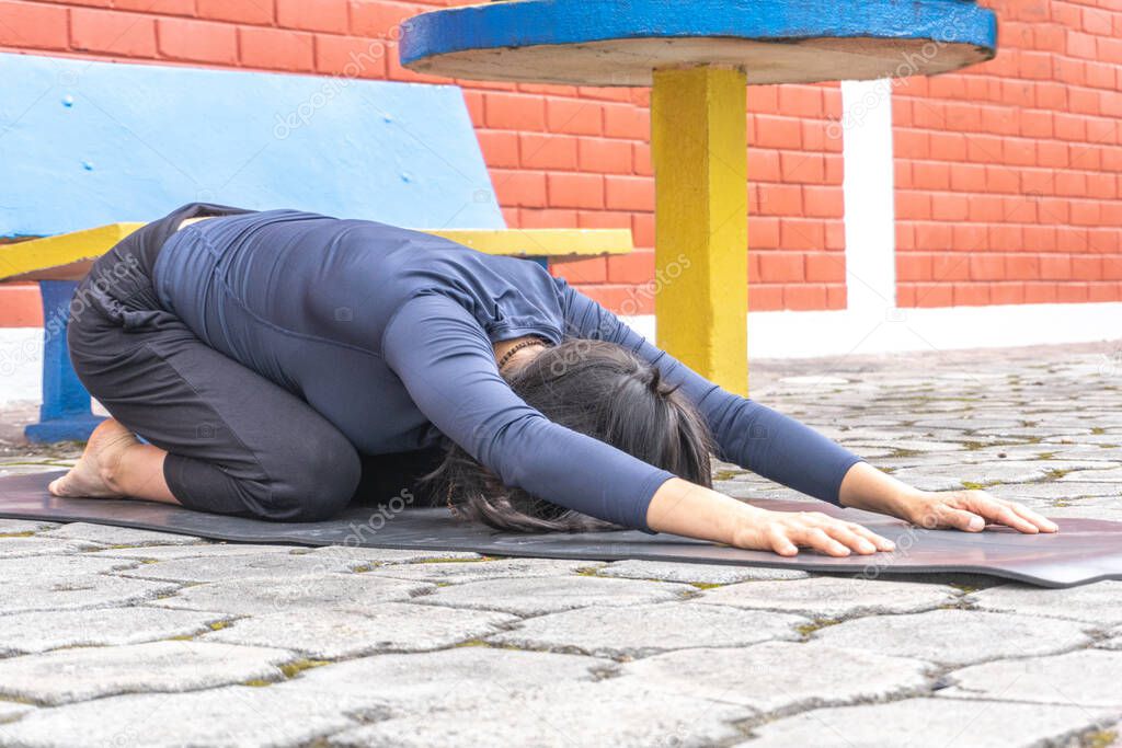 Woman practicing yoga outdoors in stretched puppy position
