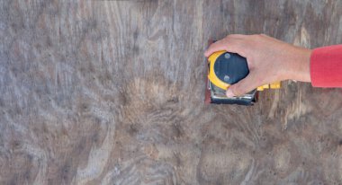 overview photo of a man's hand with an electric sander on a wooden panel doing restoration or carpentry work