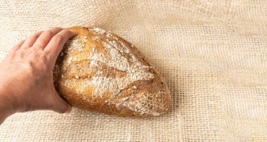 Hand taking a wholemeal bread on a sack. Bread shopping concept