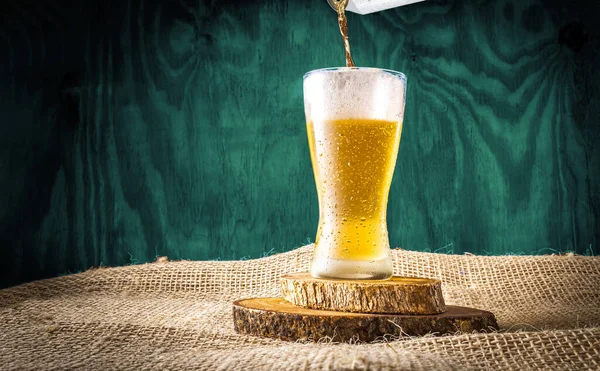 Beer can serving in a crystal glass on a blue wooden textured background