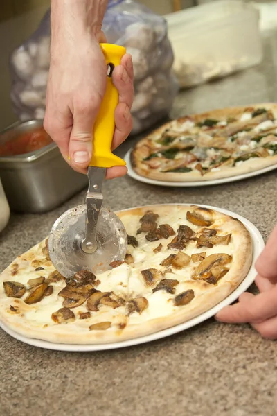 Ręka z cięcia noża pizza — Zdjęcie stockowe
