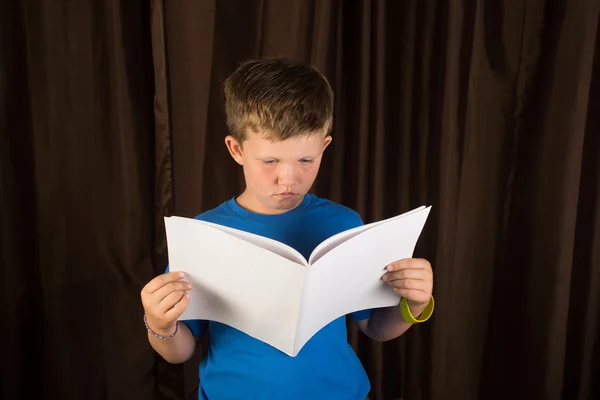 Jovem menino leitura em branco livro ou revista Imagem De Stock