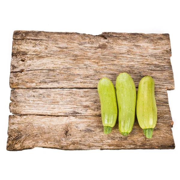 Fresh zucchini on an old wooden board isolated on white background — Stock Photo, Image