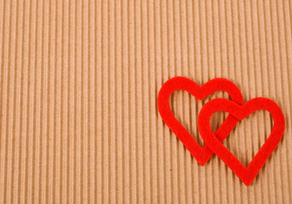 Two figures in the form of heart on the background of corrugated cardboard — Stock Photo, Image