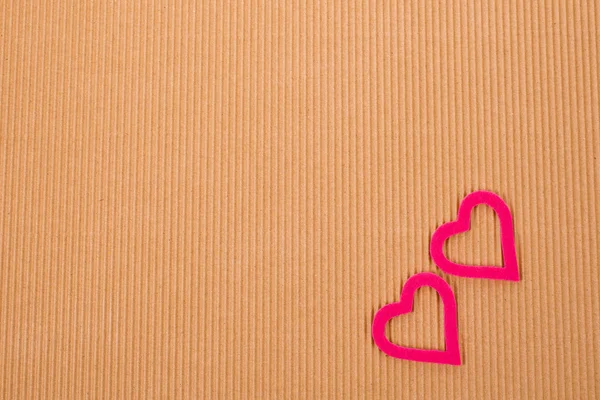 Two figures in the form of heart on the background of corrugated cardboard — Stock Photo, Image