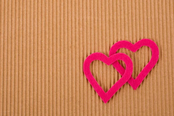 Две фигуры в виде сердца на фоне гофрированного картона — стоковое фото