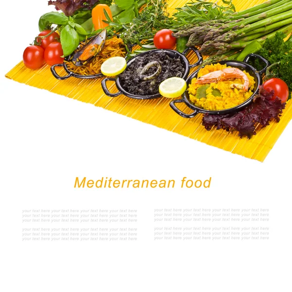 Spanish Mediterranean sea food - black rice, paella, noodles in a typical small pans on the yellow mat isolated on white background with sample text — Stock Photo, Image