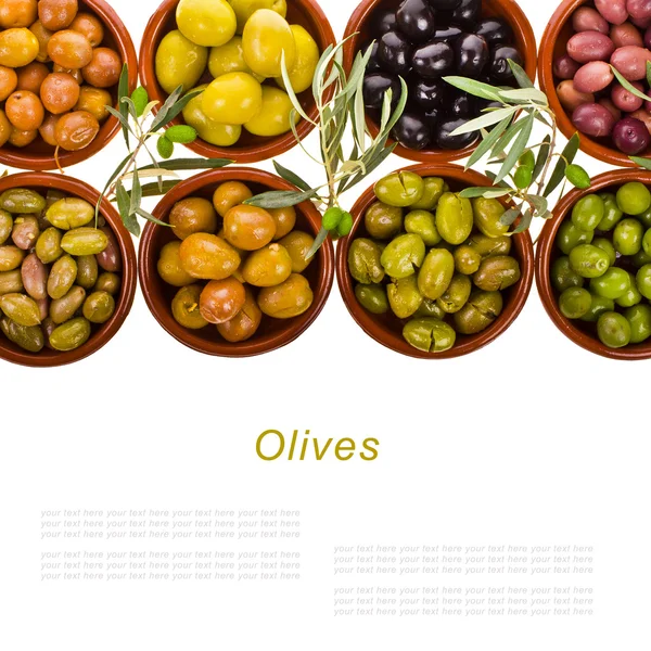 Diferentes variedades de aceitunas marinadas en cuencos tradicionales de arcilla decoradas con ramas de olivo aisladas sobre fondo blanco Fotos de stock libres de derechos