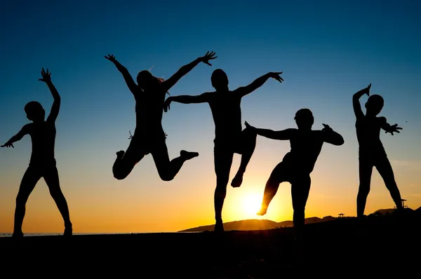 Happy kids silhouettes jumping on the beach — Stock Photo, Image