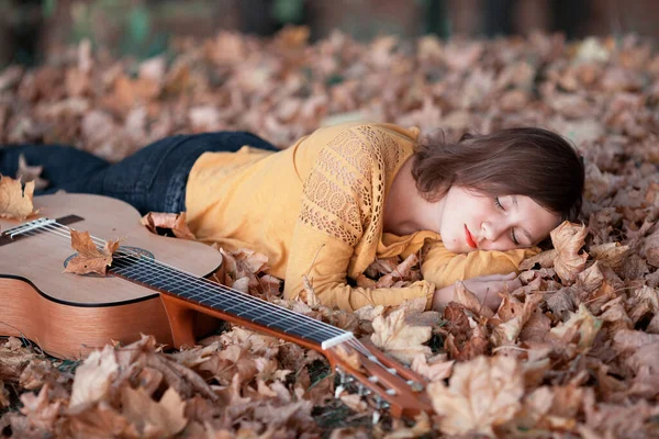 秋天公园里带着吉他的漂亮年轻女子 黄色照片 — 图库照片
