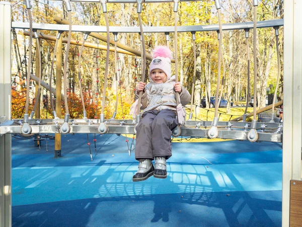 Seorang anak bermain di taman bermain pada hari musim gugur yang cerah. — Stok Foto