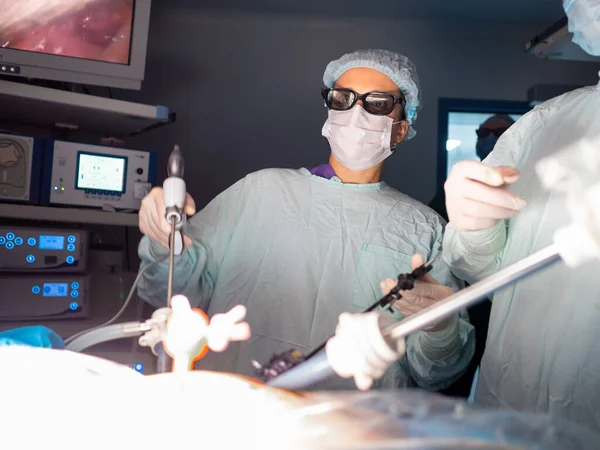 Uma mulher cirurgiã em óculos 3D realiza uma cirurgia laparoscópica — Fotografia de Stock