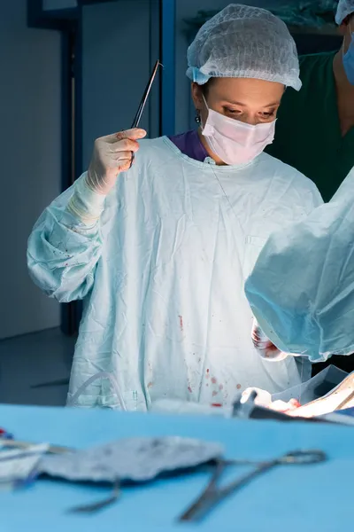 Chirurgin vernäht die Haut der Patientin während der Operation. Stockbild