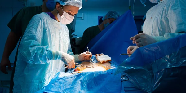 Cirujano femenino sutura la piel de los pacientes durante la cirugía. — Foto de Stock