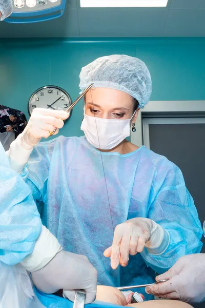 Cirujano femenino sutura la piel de los pacientes durante la cirugía. — Foto de Stock