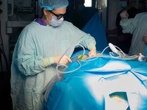 Mujer cirujana con gafas 3D sutura la piel de los pacientes después de la cirugía. — Foto de Stock