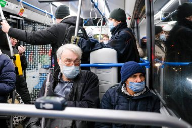Şehir otobüsünde koltuk değnekli, yüzü maske takan yaşlı, kır saçlı bir adam..