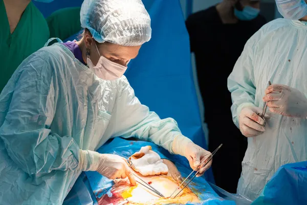 Una cirujana realiza una operación quirúrgica en un cuerpo de pacientes. — Foto de Stock