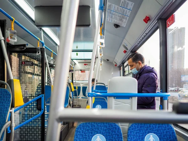 Een man met een medisch beschermend masker in een stadsbus. — Stockfoto