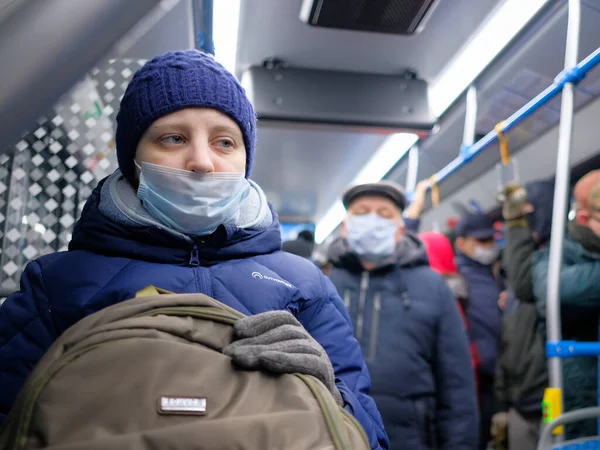 Wanita muda mengenakan masker pelindung bedah pada transportasi umum. Stok Gambar