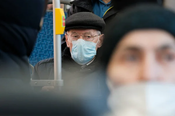 Seorang pria tua di bus kota mengenakan kacamata dan masker pelindung. Stok Gambar Bebas Royalti