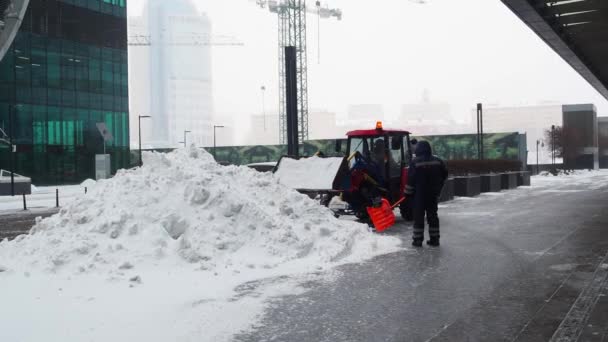 Коммунальный трактор выливает снег из ведра в большую кучу в зимний день. — стоковое видео