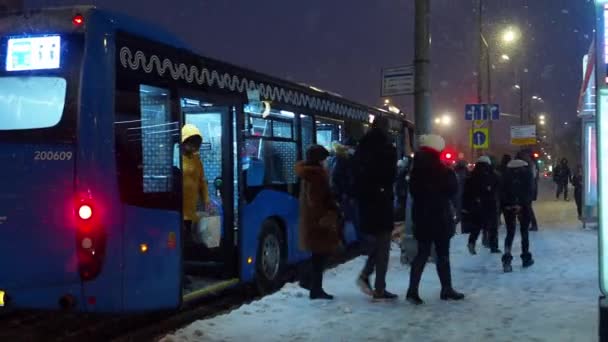 Penumpang turun dari bus listrik di halte bus selama salju turun. — Stok Video