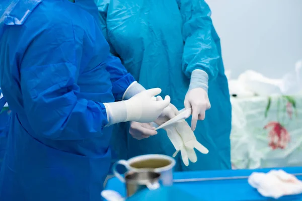 Las manos del cirujano se ponen guantes estériles antes de la cirugía.. — Foto de Stock