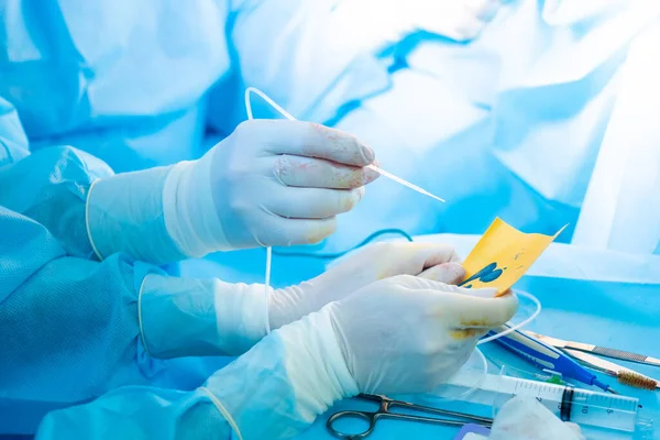 La mano de los cirujanos en un guante estéril sostiene un dispensador de pegamento de fibrina. — Foto de Stock