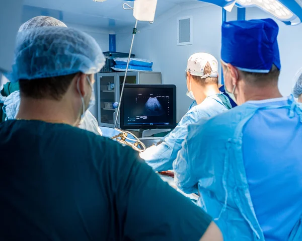 Los médicos observan un monitor de ultrasonido mientras operan a una persona. — Foto de Stock