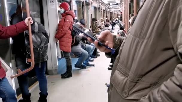 Une main de personne avec un smartphone lors d'un voyage dans une voiture de métro. — Video