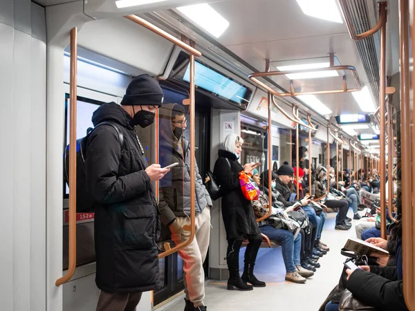 Ein Fahrgast im Schutzanzug steht in einem U-Bahn-Wagen. Stockbild
