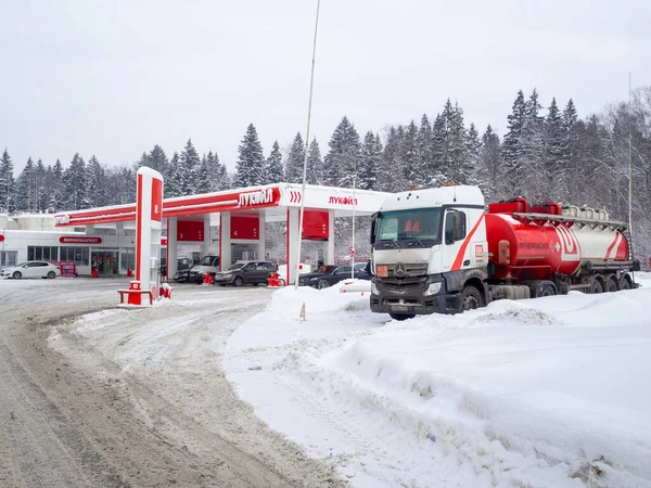 Sebuah truk tangki Mercedes Benz membongkar di sebuah pompa bensin Lukoil pada hari musim dingin. Stok Gambar