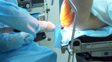The surgeon applies iodine to the patients buttocks and anus.