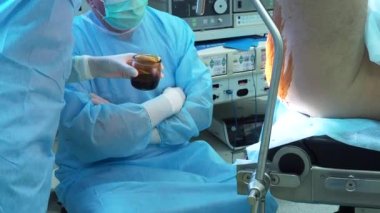 The surgeon applies iodine to the patients buttocks and anus.