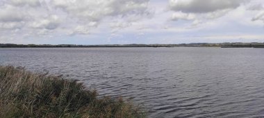 Göl, mavi gökyüzü ve bulutların arka planında